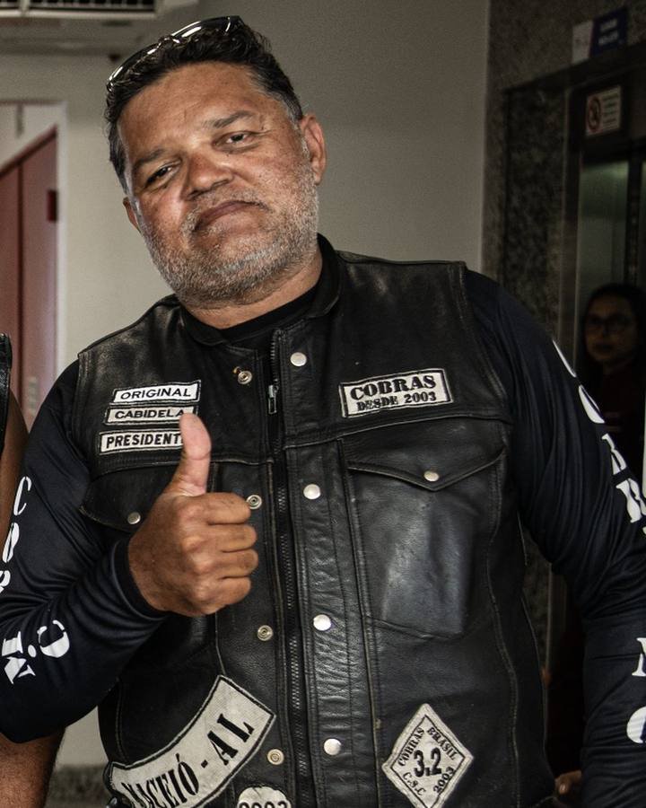 Motociclista de colete faz sinal de positivo