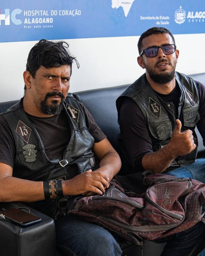 Dois motociclistas de colete sentados na recepção do Hospital do Coração Alagoano