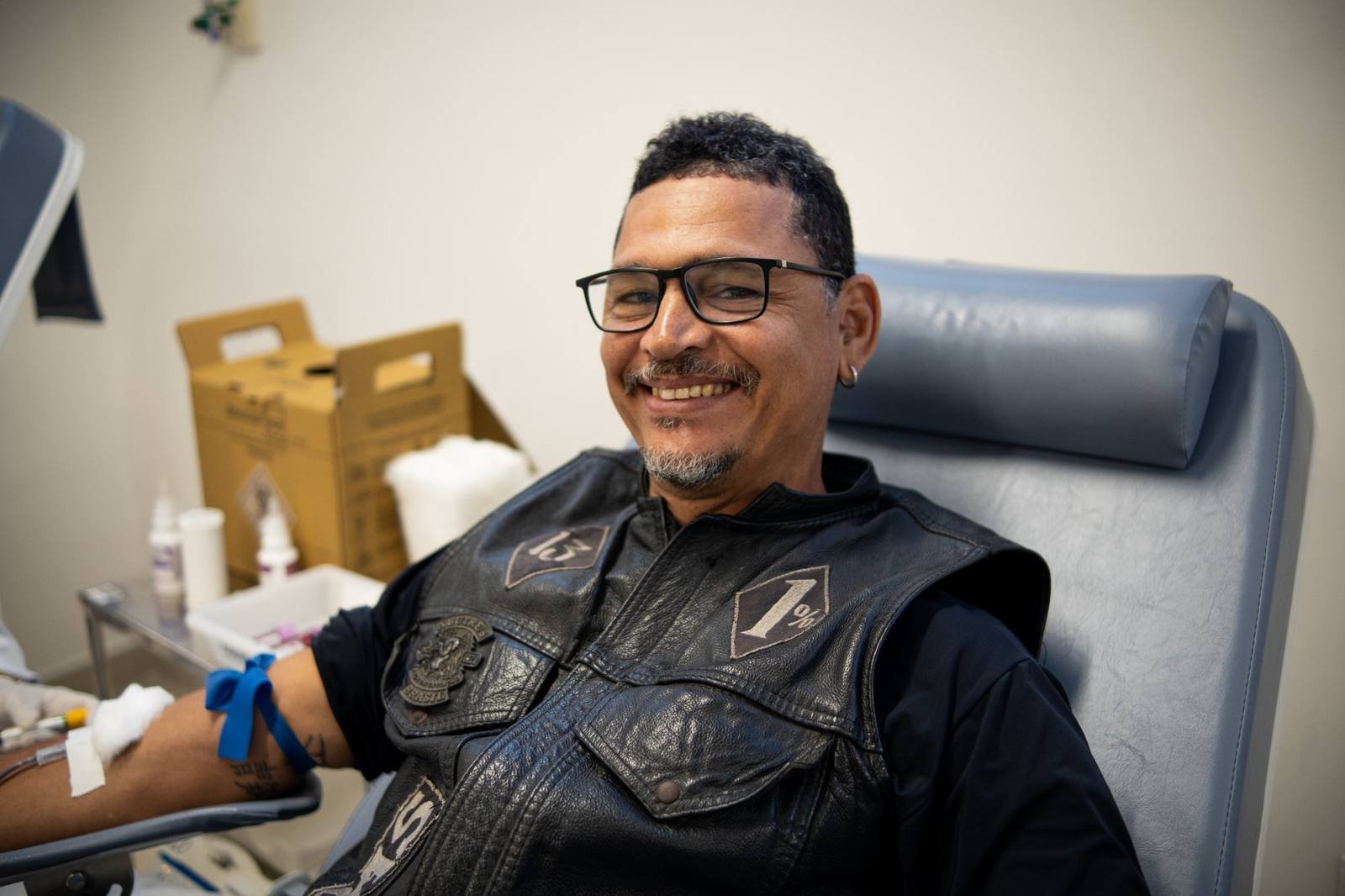 Motociclista de colete sorrindo enquanto doa sangue no Hemoal